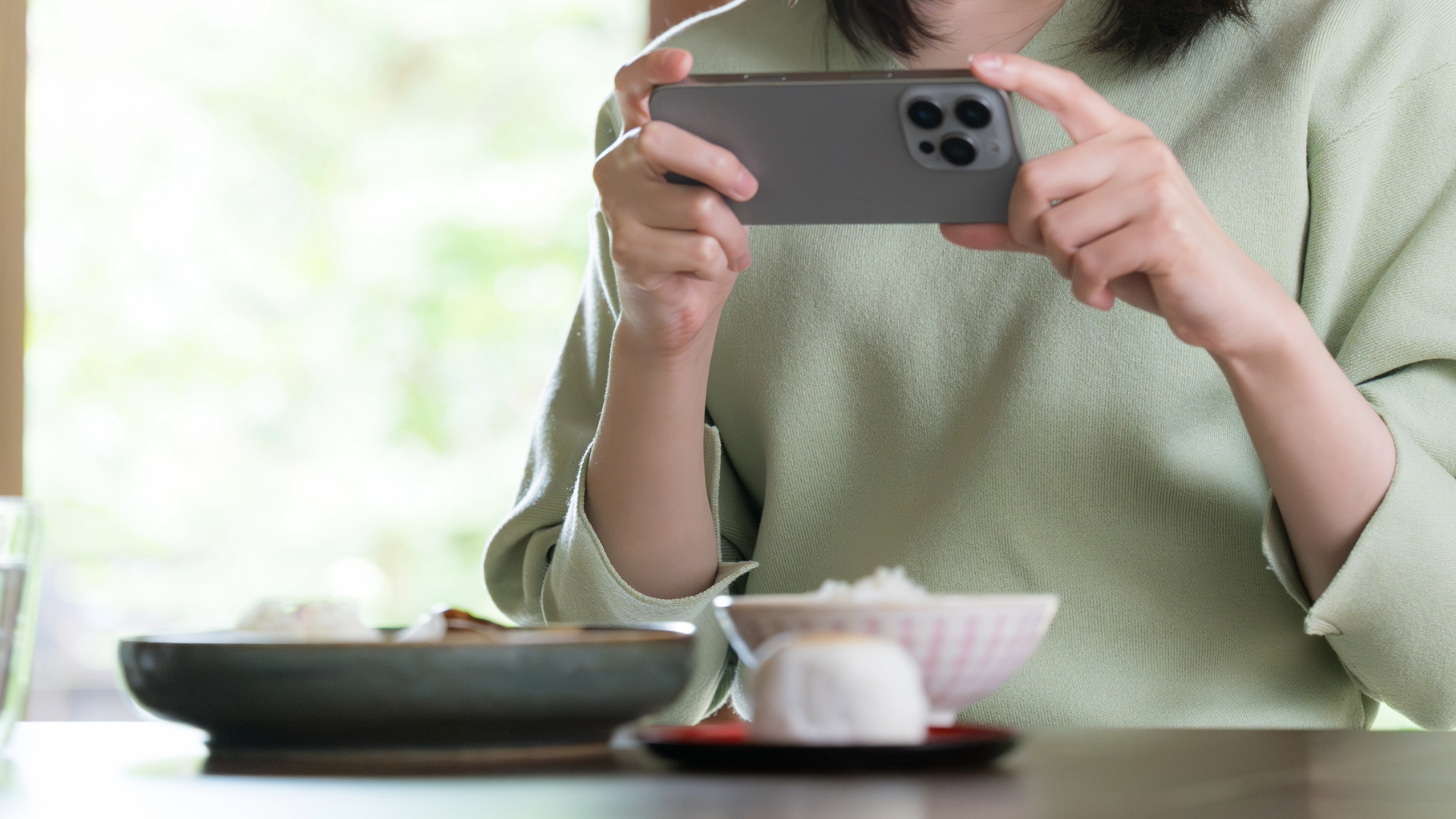 スマートフォンで食事の報告をする女性